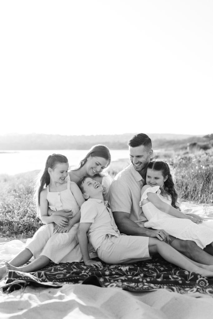 Black and white image of family of five sitting by the beach